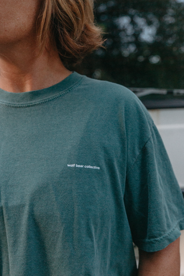 Wolf Bear Collective Origin T-Shirt in green colour lifestyle photo zoomed into the tee's logo