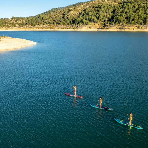 Photo of three people in each of the Jobe's paddle boards, yarra, duna and Mira on the sea with the mountains on the background